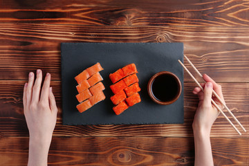 japanese roll flat lay with hand. set of california nad philodelphia rolls on slate plate and wooden background