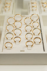 golden rings store. Wedding gold rings on the showcase. Wedding ring set. toned. vertical photo