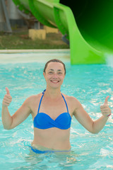 Happy girl in bikini sliding water park. Woman in a blue swimsuit. vertical photo