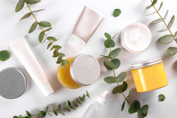Moisturizing care skincare face cream for healing complicated troubled skin type in an open jar with visible texture. Copy space, close up, background, flat lay, top view. Eucalyptus leaf decoration.