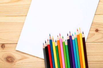 Colored pencils with notebook on brown wooden table