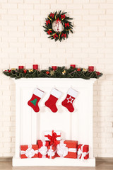 White decorated fireplace with gift boxes and wreath on brick wall background