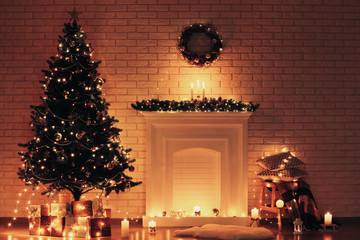 White decorated fireplace near christmas tree on brick wall background