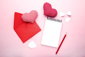 Fabric hearts with envelope, notebook and pencil on pink background