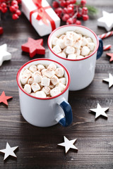 Cappuccino with marshmallows in mugs and small stars on wooden table