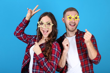 Beautiful young couple with paper booth props on blue background