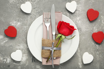 Kitchen cutlery with red rose in white plate on wooden table