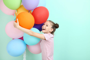 Fototapeta na wymiar Beautiful young girl with colored balloons on mint background