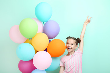 Fototapeta na wymiar Beautiful young girl with colored balloons on mint background