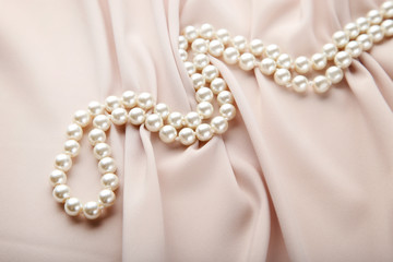 Pearl necklace on beige satin fabric