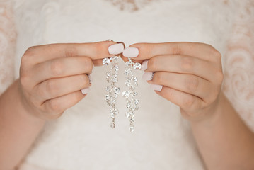 Women's wedding jewelry (earrings) in the hands of the bride, selective focus