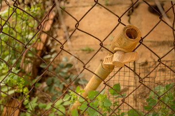 Vintage Dirty PVC Valve/ Plastic Pipe - Rusty Old Wire Fence - Green Plants