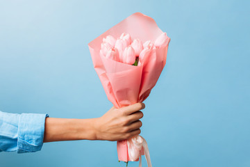 flowers in the hands of a man for Valentine's Day, on a blue background