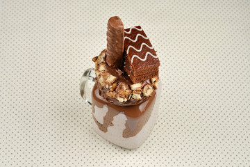 Chocolate extreme milkshake with brownie cake, chocolate paste and sweets. Crazy freakshake food trend. Copy space