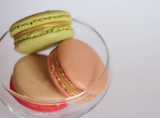 glass vase full colorful macaroons over white  background