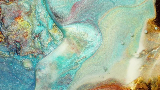 Colorful sparkling paints mix in beautiful patterns. Oil ink of blue, turquoise, yellow and other colors spread on the surface and mix one into another creating amazing textures and design.