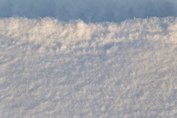 Fototapeta na wymiar Background of white snow sparkling in the sun. Shallow depth of field