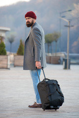 Carry travel bag. Man bearded hipster travel with luggage bag on wheels. Adjust living in new city....
