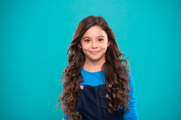 Extreme hair volume. Kid girl long healthy shiny hair. Little girl grow long hair. Teaching healthy hair care habits. Kid happy cute face with adorable curly hairstyle stand over blue background