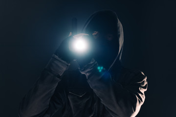 Armed burglar intruder with flashlight torch at night