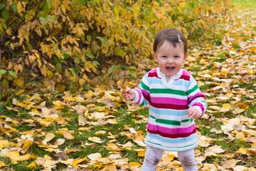 Baby girl with a handful of autumn leaves