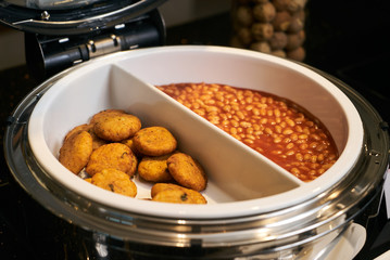 Baked beans and hash brown, close-up. Restaurant buffet catering