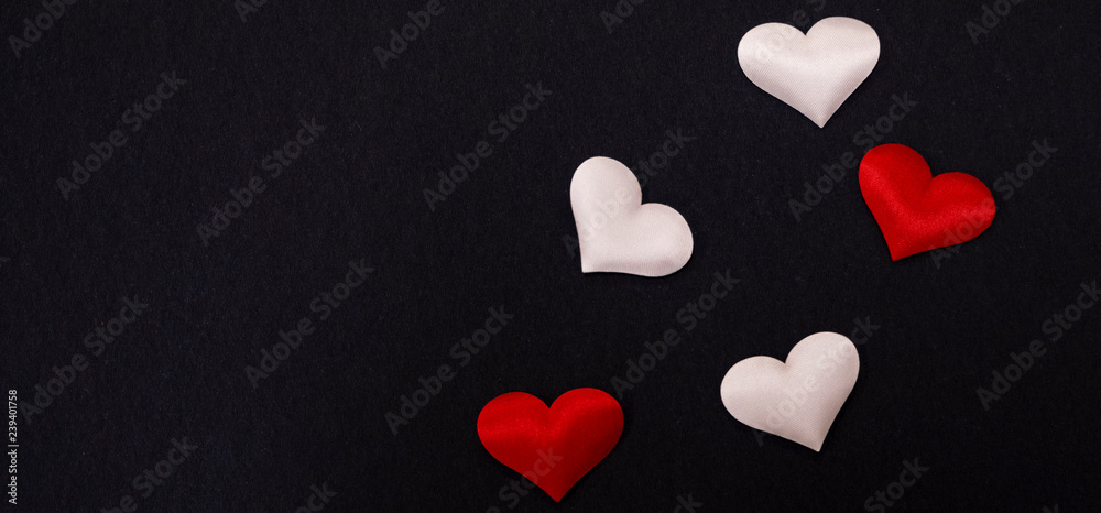 Wall mural panorama. small red and white hearts on a black background . copy space.