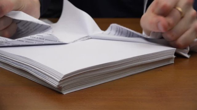 Men's hands tear documents into small pieces.
