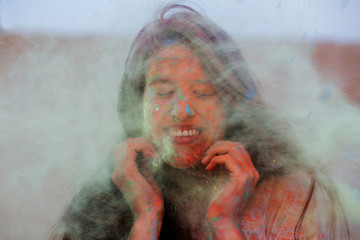 Closeup portrait of happy brunette woman playing with colorful dry paint Holi at the desert