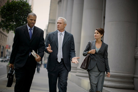 Three business colleagues walking along a street together in the city.