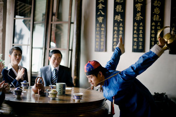 Young adult man dressed in traditional clothing doing a tea ritual in a cafe.