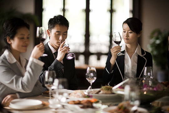 Young adult business people having a meal and wine in a restaurant.