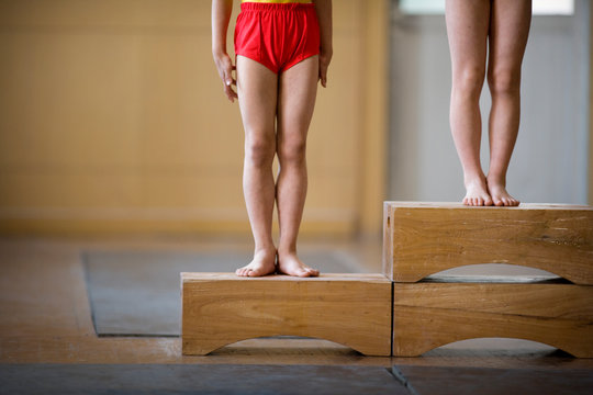 Legs of gymnasts standing on box steps.
