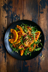 Grilled pumpking warm salad with arugula, walnuts and pomegranate seeds.Top view with copy space.