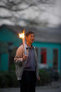 Mature adult man holding an Olympic torch in a park.