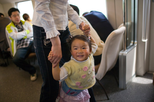 Portrait of a toddler walking with her mother on a train.