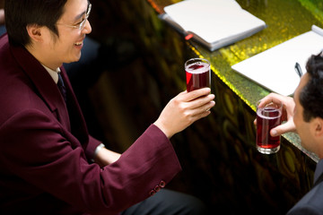 Young adult businessman drinking at a bar with a colleague.