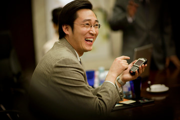 Young adult businessman using a cellphone in a boardroom.