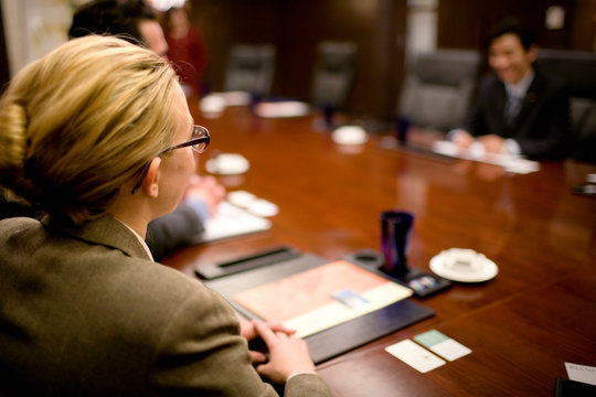 Business woman sitting with colleagues in a boardroom.