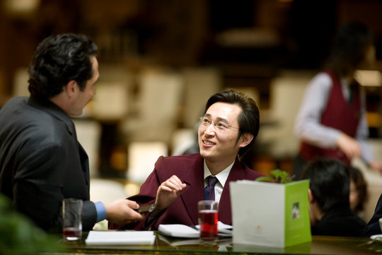 Young adult businessman drinking at a bar with a colleague.