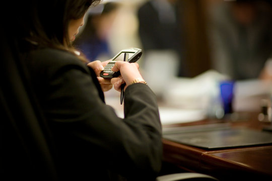 Cellphone being used by a business woman in a boardroom.