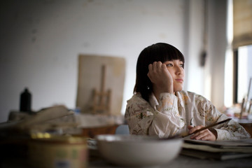 Teenage girl painting in a classroom.