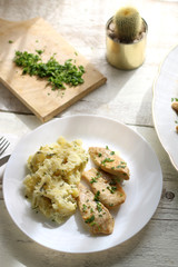 Grilled chicken with fresh parsley and mashed potatoes on a rustic white table. Selective focus.