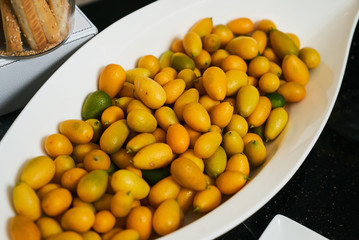 Fresh Kumquat Kinkan or Fortunella plate on black kitchen table
