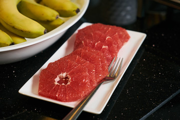 Fresh sliced grapefruit plate on black kitchen table, close-up