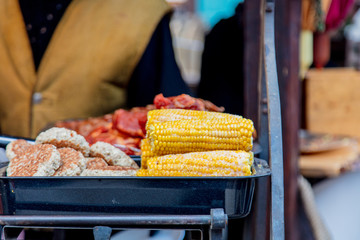 Traditional european grilled meat and corn with smoke on Christmas fair