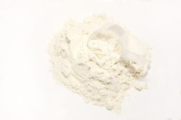 heap of whey protein powder with plastic spoon on white background