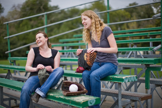 Friends sitting on bleachers at sport field