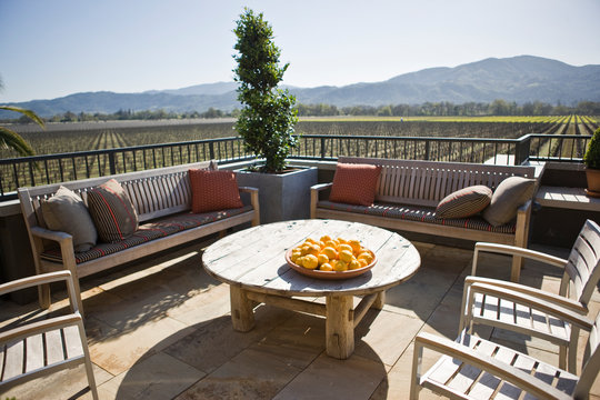 Plate of oranges on a table surrounded by chairs on an outdoor patio.