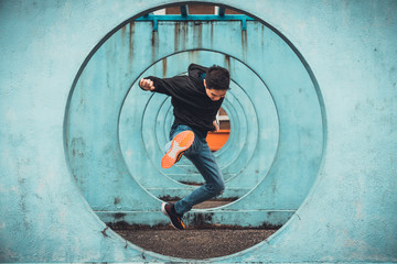 Young Asian active man jumping and kicking action, circle looping wall background. Extreme sport...